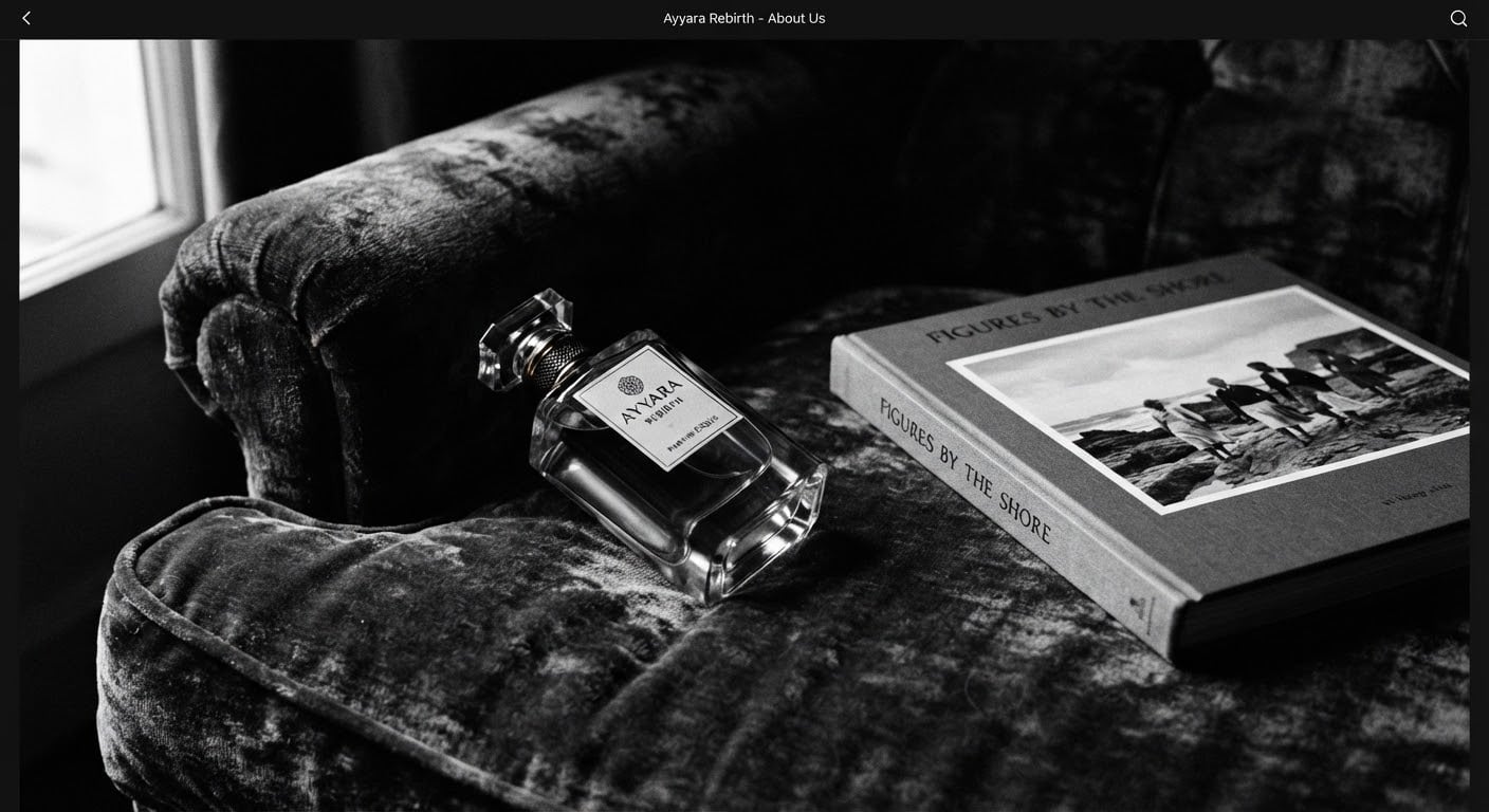 Clear glass luxury perfume bottle resting on deep velvet vintage armchair beside art monograph book